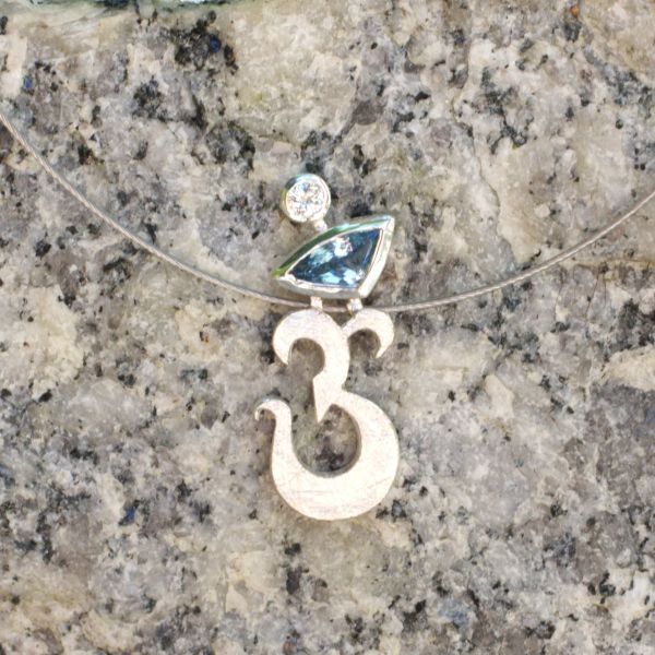 Anhänger in Form eines Om-Zeichens aus Silber mit zwei Steinen